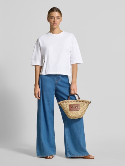 Modelka kobieca nosi T-Shirt mit überschnittenen Schultern Modell 'Sarenzi' od OPUS z czystej bawełny, krój loose fit, okrągły dekolt, białe, szerokie rękawy, szerokie niebieskie jeansy, pleciona torba, pełny widok z przodu.
