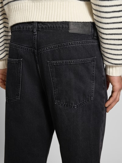 Mężczyzna nosi Tapered Fit Jeans aus reiner Baumwolle Modell 'RUNNE' von Marc O'Polo Denim, czarny melanż, denim, naszywka, detal paskowy, 5 kieszeni, szerokość w rozmiarze 32/32: 42 cm, długość nogawki: 73 cm, zdjęcie z tyłu, zbliżenie na biodra.