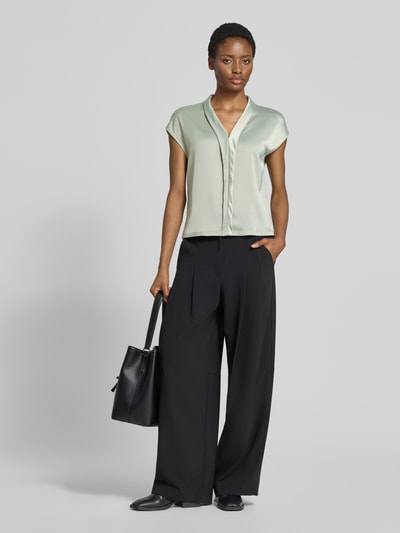 Frauenmodel trägt Regular Fit T-Shirt aus Viskose-Mix von s.Oliver BLACK LABEL in hellem Grün, kombiniert mit schwarzer Hose, Ganzkörperansicht von vorne.