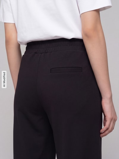 Frauenmodel trägt Hose mit weitem Bein Modell 'KATE' von ICHI, unifarben Schwarz, elastischer Bund, Gesäßtasche, Nahaufnahme Rückansicht, KI-modifiziertes Bild.