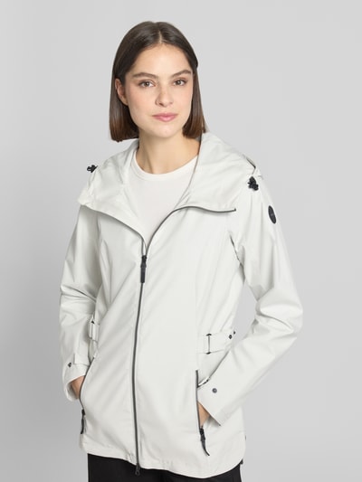 Vrouwenmodel draagt Regular Fit Regenmantel met logodetail van G.I.G.A. dx, lichtgrijs, steekzakken, capuchon met tunnelkoord, tweewegritssluiting, ruglengte 76 cm, schouderbreedte 40 cm, borstwijdte 50 cm, mouwlengte 66 cm, geheel vooraanzicht.