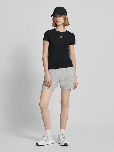 Frauenmodel trägt Slim Fit T-Shirt mit Motiv-Stitching von REVIEW, Damen T-Shirt aus elastischem Baumwoll-Mix, Schwarz, Rundhalsausschnitt, Rückenlänge bei Größe S 55 cm, Ganzkörperansicht von vorne.