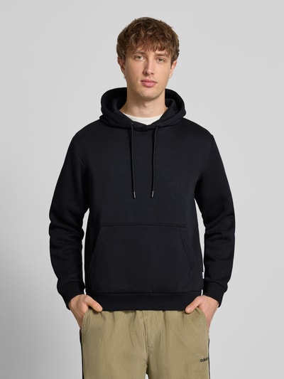 Männermodel trägt Hoodie mit Kapuze Modell 'BRADLEY' von Jack & Jones in Schwarz, lockerer Schnitt, Baumwoll-Mix, Ganzkörperansicht von vorne.