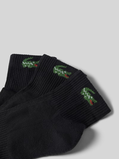 Produktfoto, schwarze Socken aus Baumwoll-Mix im 3er-Pack von Lacoste, feine Struktur, sichtbares grünes Krokodil-Logo, Herren Socken