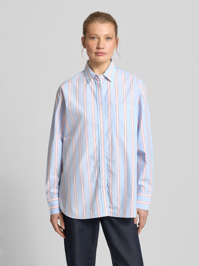 Frauenmodel trägt Oversized Hemdbluse aus reiner Baumwolle von Lacoste, Optik:Allover-Muster, Passform: Oversized, Hemdkragen, Label-Stitching-Applikation, einreihige Knopfleiste, Langarm mit Manschette, Brusttasche, Materialverarbeitung: Popeline, Material: reine Baumwolle, zarte Streifen in Blau und Weiß, glatte Oberfläche, Ganzkörperansicht von vorne.
