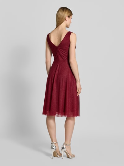 Modelka prezentuje knielanges Cocktailkleid mit V-Ausschnitt von TROYDEN COLLECTION, bordowy szyfon, krój taliowany, szerokie ramiączka, długość do kolan, głęboki dekolt V z tyłu, suwak na plecach, długość tyłu w rozmiarze 36: 85 cm, szerokość w rozmiarze 36: 43 cm, widok całej sylwetki od tyłu.