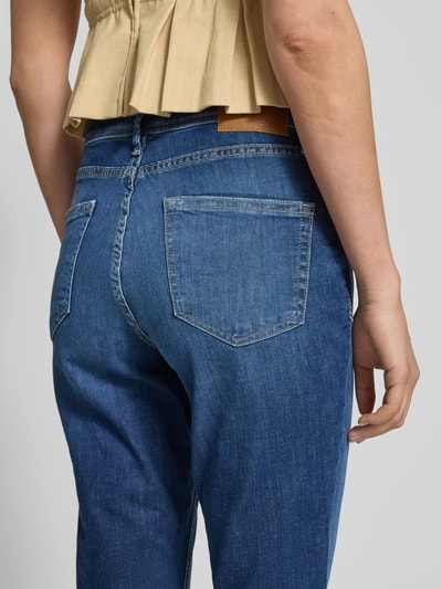 Frauenmodel trägt Slim Fit Caprijeans aus Baumwoll-Mix Modell 'BETSY' von s.Oliver RED LABEL in mittlerem Denimblau, Detailaufnahme Rückansicht. 7/8-Länge, 5-Pocket-Design, Label Patch sichtbar, strukturierte Baumwoll-Textur.