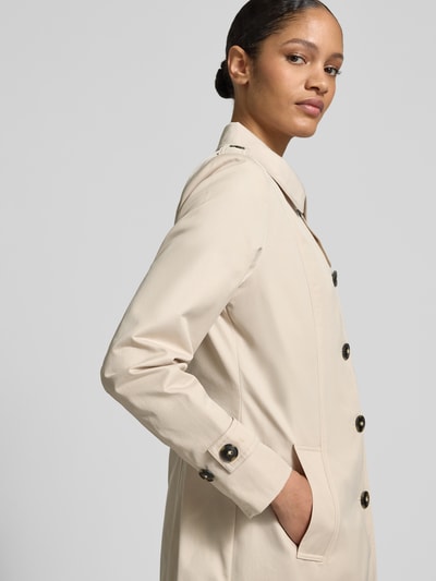 Frauenmodel trägt Trenchcoat mit Ärmelriegeln von Fuchs Schmitt in Beige, glatte Textur, sichtbare Knopfleiste, Nahaufnahme Oberkörper. Regular Fit, Umlegekragen, Eingrifftaschen, Rückenlänge 78 cm, Schulterbreite 39 cm, Brustweite 49 cm, Ärmellänge 63 cm.