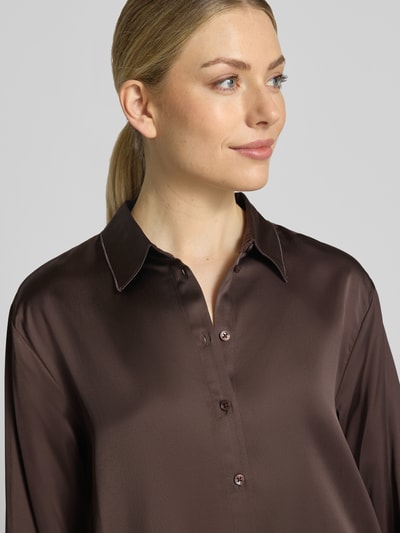 Frauenmodel trägt Relaxed Fit Hemdbluse aus Viskose-Mix von COMMA in Dunkelbraun mit Hemdblusenkragen und Knopfleiste, Nahaufnahme Oberkörper. Rückenlänge 69 cm und Ärmellänge 60 cm bei Größe 36.
