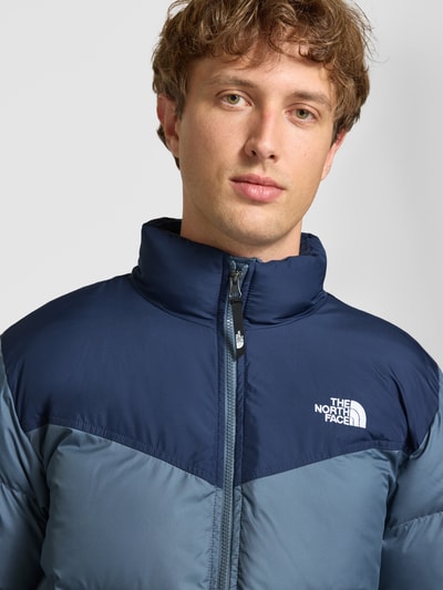 Männermodel trägt Regular Fit Jacke in Stepp-Optik Modell 'SAIKURU' von The North Face in Dunkelblau und Grau, Nahaufnahme Oberkörper.