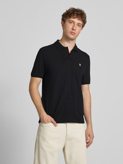 Männermodel trägt Modern Fit Poloshirt mit Logo-Stitching von REVIEW aus schwarzem Baumwoll-Mix, Polokragen, kurze Knopfleiste, Rückenlänge 65 cm bei Größe M, Ganzkörperansicht von vorne.