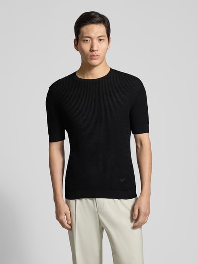 Männermodel trägt Slim Fit T-Shirt mit Seiden-Anteil in Strick-Optik von Emporio Armani, Schwarz, Baumwoll-Mix, Ganzkörperansicht von vorne.