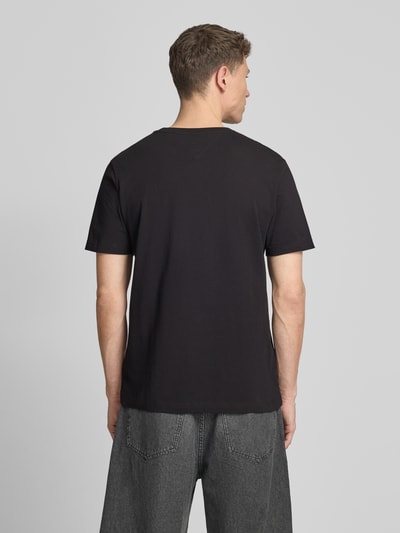 Männermodel trägt Regular Fit T-Shirt aus reiner Baumwolle von Tommy Hilfiger, Optik: Unifarben, Label-Print, Ganzkörperansicht Rückansicht.