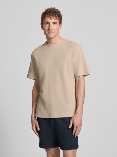 Männermodel trägt Regular Fit T-Shirt aus Baumwoll-Mix Modell 'TOBIE' von Only & Sons in Beige mit Waffel-Struktur, Ganzkörperansicht von vorne.