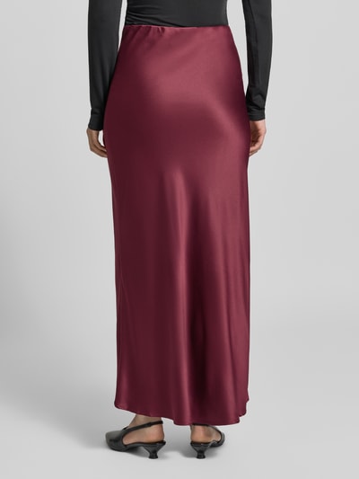 Männermodel trägt Ausgestellter Maxi-Rock mit elastischem Bund Modell 'MERLE' von VERO MODA in dunklem Rot mit leicht glänzender, glatter Textur, Ganzkörperansicht Rückansicht, Damen Maxi-Rock von VERO MODA