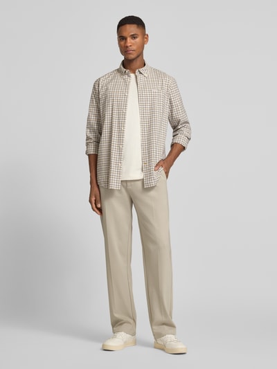 Männermodel trägt Slim Fit Hose aus Viskose-Mix Modell 'ALTON' von Guess in Beige, mit Bundfalten, Eingrifftaschen, Ganzkörperansicht von vorne.