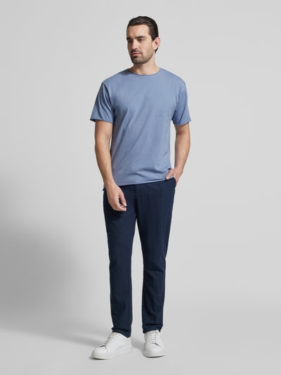Männermodel trägt T-Shirt mit Rundhalsausschnitt und Label-Detail von Scotch & Soda, Reine Baumwolle, Regular-Fit, Rollsaum, Ganzkörperansicht von vorne.