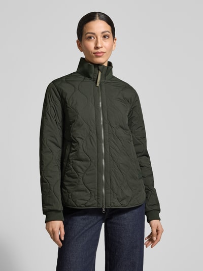 Vrouwenmodel draagt Steppjacke mit Stehkragen van camel active in donkergroen, rechte fit, elastische mouwboorden, detailopname bovenlichaam.