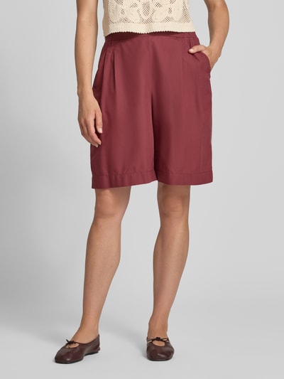Modelka nosi Relaxed Fit Bermuda aus reiner Baumwolle od s.Oliver RED LABEL, bordowy kolor, prosta faktura, zbliżenie na nogi.