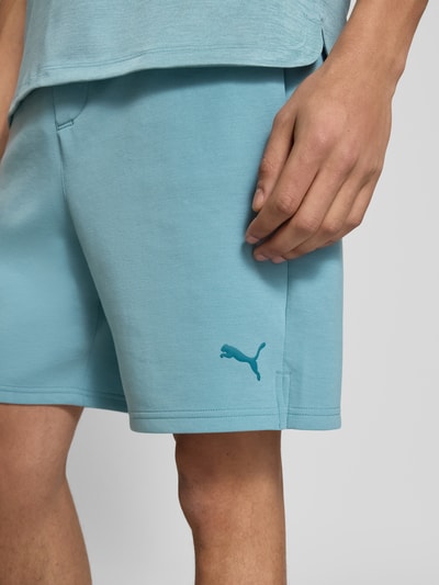 Männermodel trägt Straight Fit Shorts mit Lyocell-Anteil Modell 'Cloudspun' von PUMA PERFORMANCE in Hellblau mit Logo, Nahaufnahme Oberschenkel, elastischer Bund, seitliche Tasche, weiche Textur, Kontext: Herren Shorts mit Gesäßtasche und Tunnelzug.