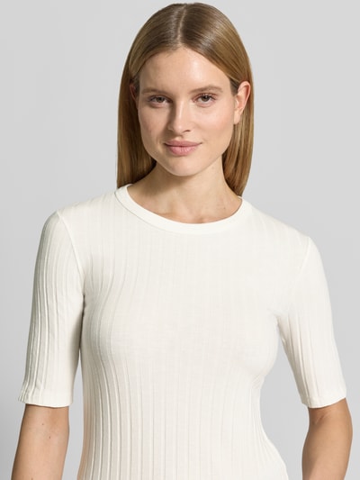 Kobiece model nosi damski t-shirt w kolorze kremowym, efekt prążkowania, okrągły dekolt, krój slim fit, mieszanka materiałów z dodatkiem streczu, model 'Savka' od OPUS, rękaw o dł. 1/2, długość tyłu w rozmiarze 36: 56 cm, zbliżenie na górną część ciała