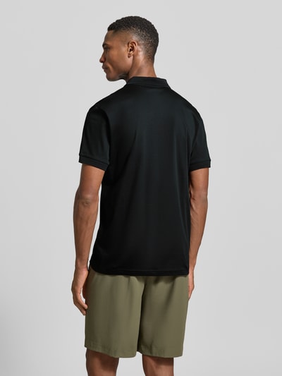 Männermodel trägt Regular Fit Poloshirt aus reiner Baumwolle Modell 'PS Spirit 70 Plk' von BOSS Green X PORSCHE, unifarben, Ganzkörperansicht Rückansicht.