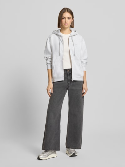 Vrouwenmodel draagt Sweatjacke mit Kapuze van Levi's®, lichtgrijs, katoenmix, losse pasvorm, capuchon, rits, zakken, vooraanzicht.