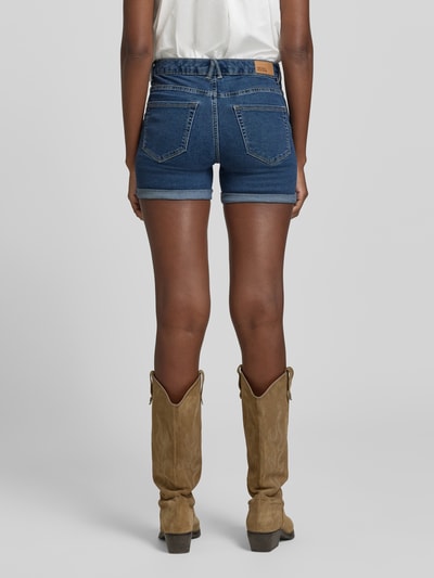 Frauenmodel trägt Regular Fit Jeansshorts aus Baumwoll-Mix Modell 'LUNA' von Vero Moda, Denim-Optik, Label-Patch, 5-Pocket-Design, Beinabschluss mit fixiertem Umschlag, Knopf und verdeckter Reißverschluss, Ganzkörperansicht Rückansicht.