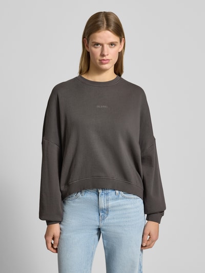 Frauenmodel trägt Oversized Sweatshirt mit Label-Stitching von OH APRIL aus reiner Baumwolle, anthrazitfarben, Rundhalsausschnitt, Nahaufnahme Oberkörper.