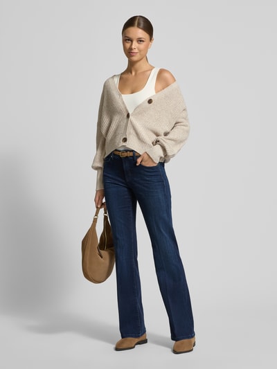 Vrouwenmodel draagt Relaxed Fit Strickjacke met V-hals model 'LEA' van Vero Moda in melange optiek, knoopsluiting, vooraanzicht volledige lengte.