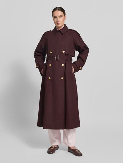 Kobiece model prezentuje Oversized Trenchcoat aus reiner Baumwolle od Tommy Hilfiger, jednokolorowy bordowy trencz z pagonami, kontrafałdą, paskiem w talii, długie rękawy z patkami, hydrofobowy, wpuszczane kieszenie, bawełna, pełny widok z przodu.