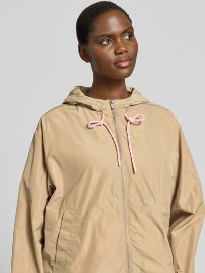 Frauenmodel trägt Jacke mit Kapuze und Zweiwege-Reißverschluss von Smith and Soul in Beige, Eingrifftaschen, entspannter Schnitt, Nahaufnahme Oberkörper.
