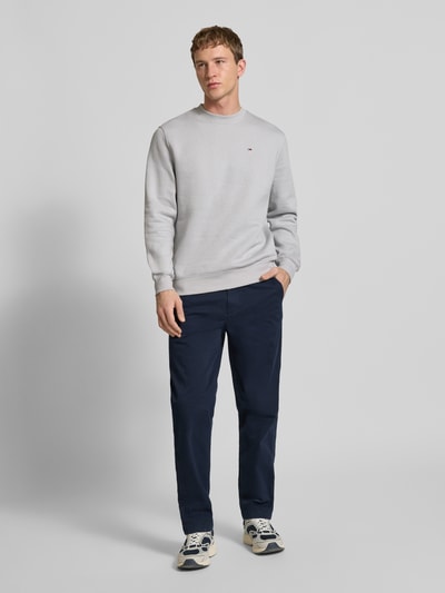 Männermodel trägt Tapered Chino aus Baumwoll-Mix Modell 'SONNY' von Tommy Jeans in Dunkelblau, Optik: Unifarben, Regular-Fit, Ganzkörperansicht von vorne.