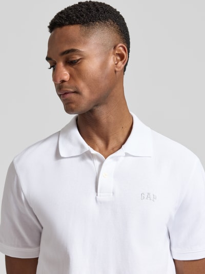 Männermodel trägt weißes Slim Fit Poloshirt mit Label-Stitching von GAP, Baumwoll-Elasthan-Mix, Nahaufnahme Oberkörper.