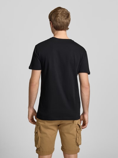 Männermodel trägt T-Shirt mit Logo und Rundhalsausschnitt von Alpha Industries aus Reine Baumwolle, Regular-Fit, Rückenlänge 68 cm, Ganzkörperansicht Rückansicht.