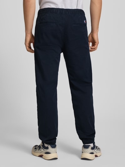 Männermodel trägt Straight Fit Jeans aus reiner Baumwolle von Tommy Jeans in dunkelblau mit elastischem Bund, denim look, 5-pocket-design, ganzkörperansicht rückansicht.