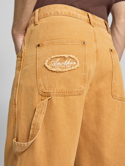 Mężczyzna nosi Relaxed Fit Jorts mit Eingrifftaschen von ANOTHER COTTON LAB, bawełna, szerokość w rozmiarze M 45 cm, długość wewnętrzna nogawki 26 cm, wpuszczane kieszenie, zapięcie na guzik i zamek błyskawiczny, widok z tyłu z bliska.