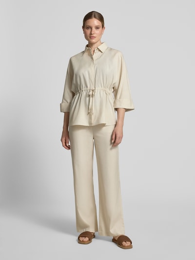 Frauenmodel trägt Relaxed Fit Bluse aus Lyocell-Mix mit 3/4-Arm von Comma in Beige, Hemdblusenkragen, Tunnelzug, Ganzkörperansicht von vorne, Rückenlänge 71 cm, Ärmellänge 58 cm, Lyocell-Mix mit Leinen-Anteil.