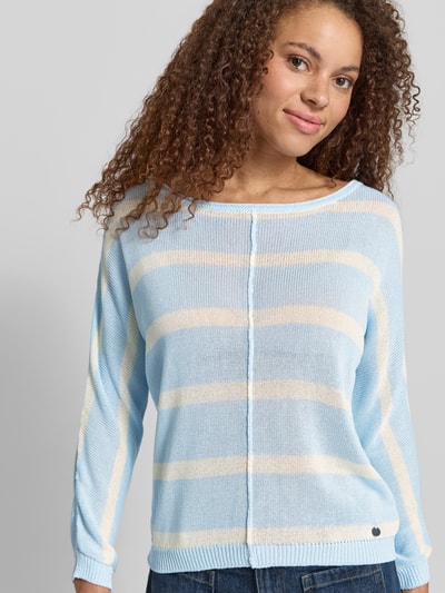 Frauenmodel trägt Boxy Fit Strickpullover aus Viskose-Mix Modell 'ALBERTA' von Pepe Jeans in Strickoptik, Struktur, Label-Applikation, U-Boot-Ausschnitt, Langarm, gerippte Abschlüsse, hellblau mit cremefarbenen Streifen, Materialverarbeitung: Strick, Muster: Struktur, Nahaufnahme Oberkörper.