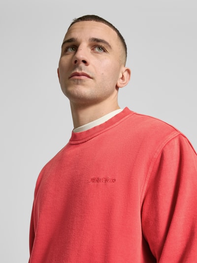 Mannenmodel draagt Sweatshirt mit Label-Stitching und Rundhalsausschnitt van Dickies in katoenmix, relaxed fit, rood, Nahaufnahme bovenlichaam.