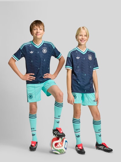 Junge trägt Regular Fit Auswärtstrikot mit DFB-Applikation von adidas Sportswear, Optik: Unifarben, Passform: Regular-Fit, Jacquard, Kontraststreifen, Logo-Stitching, V-Ausschnitt, Ärmelform: Kurzarm, Nahaufnahme Ganzkörperansicht von vorne.