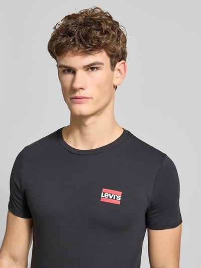 Męski model nosi T-shirt mit Label-Print im 2er-Pack von LEVI'S®, bawełna, krój slim fit, okrągły dekolt, nadruk z logo, zestaw 2 szt., Nahaufnahme górnej części ciała.