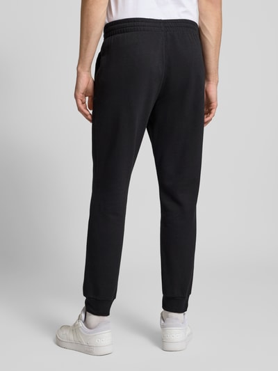 Männermodel trägt Regular Fit Sweat-Anzug aus Baumwoll-Mix von adidas Sportswear, Optik: Unifarben, Ganzkörperansicht Rückansicht.