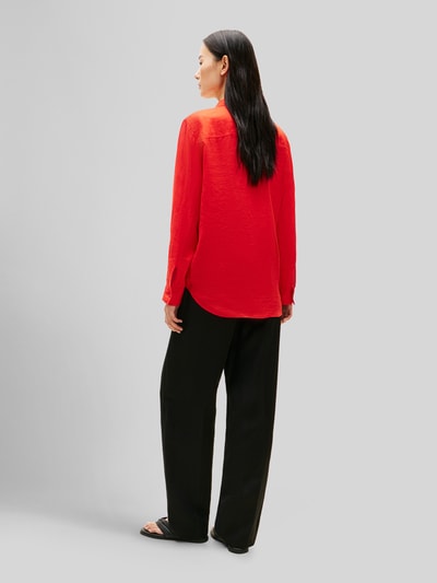 Frauenmodel trägt Relaxed Fit Langarmbluse aus reinem Leinen von Tommy Hilfiger, Optik: Unifarben, Passform: Relaxed-Fit, Kragenform: Hemdkragen, Applikation: Logo-Stitching, Verschluss: Knopfleiste, Ärmelform: langarm, Ärmelabschluss: Manschette, Rumpfabschluss: abgerundet, Materialverarbeitung: Flammgarn, Material: Leinen, in Rot, kombiniert mit schwarzer Hose, Textur leicht strukturiert, Ganzkörperansicht Rückansicht.