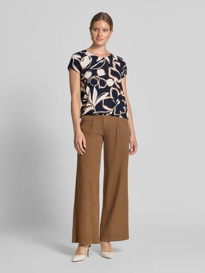 Frauenmodel trägt Regular Fit T-Shirt aus Viskose-Mix von Betty Barclay mit abstraktem Muster in Dunkelblau und Beige, kombiniert zu brauner Hose, Ganzkörperansicht von vorne. Damen T-Shirt von Betty Barclay.