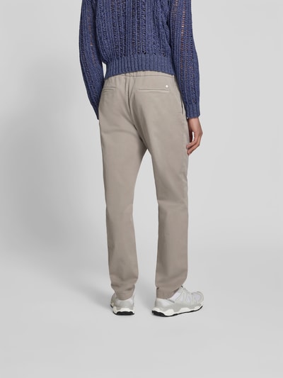 Männermodel trägt Slim Fit Stoffhose mit Tunnelzug von Closed in Beige, Baumwoll-Mix, Eingriff- und Gesäßtaschen, Rückansicht Ganzkörperansicht.