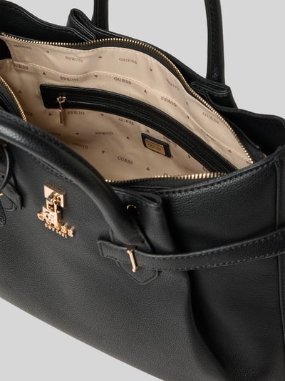 Produktfoto, czarna Handtasche in Leder-Optik mit Logo-Applikation von Guess, faktura skóry, złote detale, przegroda na zamek, widok wnętrza.