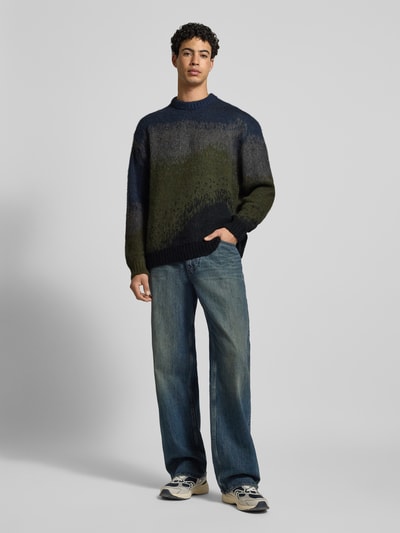 Männermodel trägt Strickpullover mit Rundhalsausschnitt Modell 'TINLEY' von Carhartt Work In Progress, gerade Form, Blau-Grün, Ganzkörperansicht von vorne.