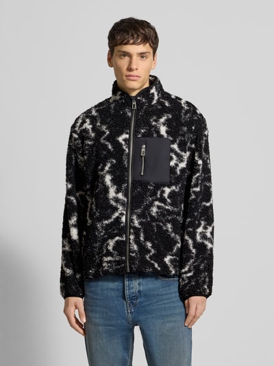 Męski model nosi Regular Fit Futerko-Kurtka z wzorem na całej powierzchni model 'JAIMY' od Only & Sons, czarno-białe kolory, prosty design, kieszeń na piersi, długi rękaw, stójka, elastische zakończenia rękawów, tunel u dołu, wykończenie materiału: futerko, zamknięcie na zamek błyskawiczny, widok na całe ciało z przodu.