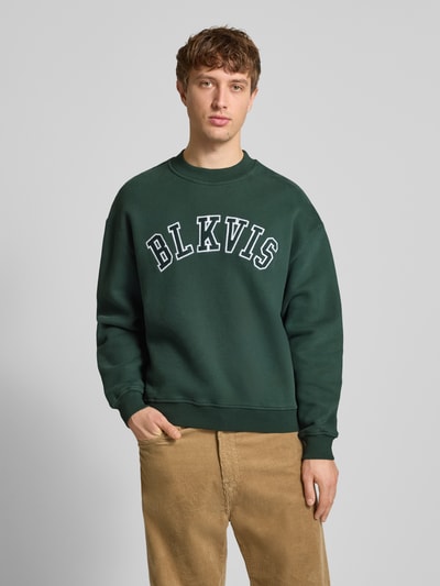Männermodel trägt Sweatshirt mit Logo und Rundhalsausschnitt von BLKVIS, grün, Reine Baumwolle, Relaxed-Fit, Ganzkörperansicht von vorne.